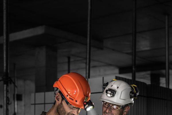 Zwei Männer in Baustellenmontur lesen einen Plan.