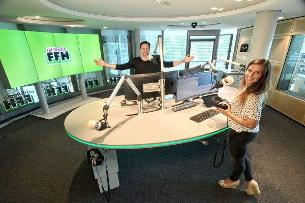 Zwei Radiomoderatoren stehen in einem Studio.