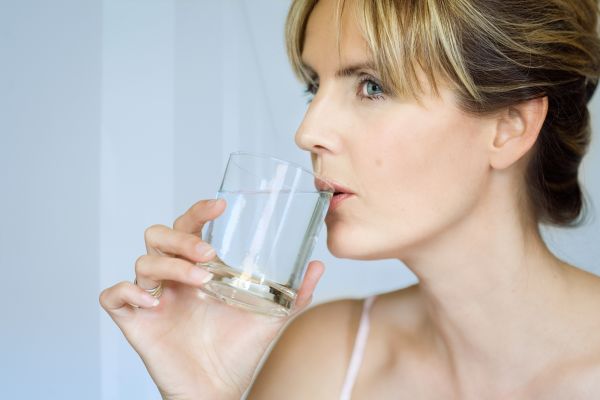 Eine Frau trinkt aus einem Glas Wasser.