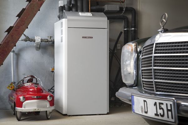 Eine Wärmepumpe steht neben einem Auto in einer Garage.