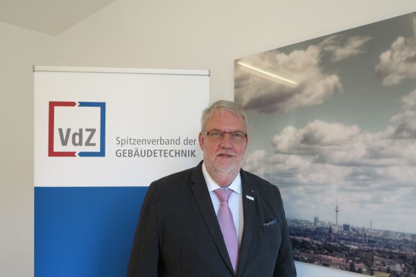Das Bild zeigt den neuen VdZ-Präsidenten Friedrich Budde vor einer VdZ-Werbetafel.
