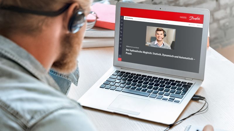 Das Bild zeigt einen Mann, der auf den Bildschirm seines Laptops schaut und an einem Webinar von Danfoss teilnimmt.