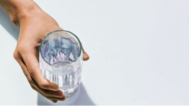 Das Bild zeigt eine Hand am Wasserglas.