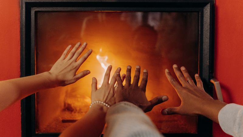 Das Bild zeigt Hände, die sich am Ofen wärmen.
