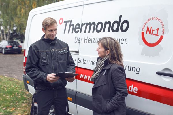 Das Bild zeigt einen Thermondo-Mitarbeiter im Gespräch mit einer Kundin vor dem Firmenwagen.