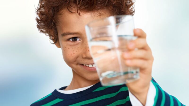 Das Bild zeigt ein Kind mit Wasserglas.