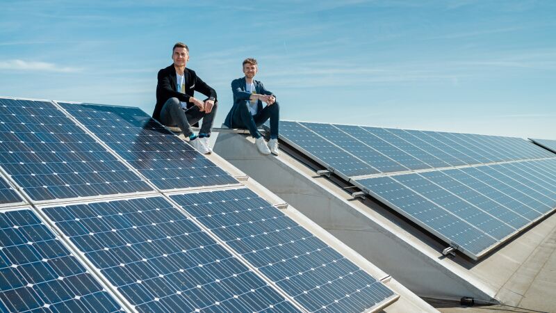 Zwei Personen sitzen auf einer Solaranlage