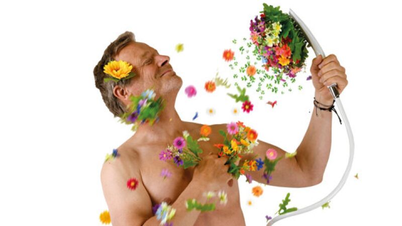 Das Bild zeigt einen Mann mit einer Handbrause, aus der Blumen statt Wasser „fließen“.