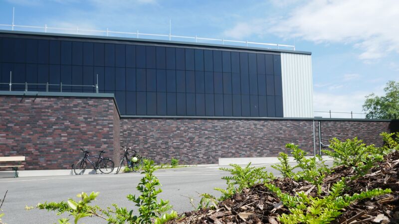 Außen fällt die sanierte Sporthalle des Lippe Berufskollegs in Lünen durch ihre Photovoltaik-Fassade auf.