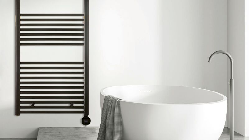Das Bild zeigt einen schwarzen Badheizkörper neben einer Badewanne.