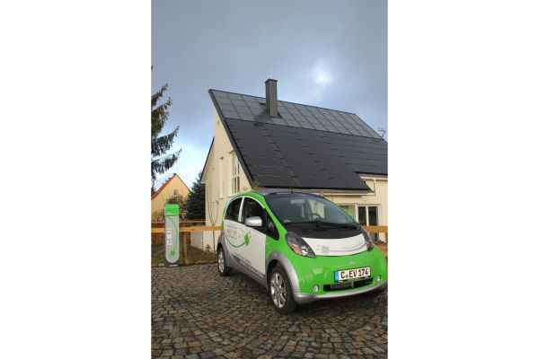Ein Elektroauto tankt am energieautarken Haus auf.