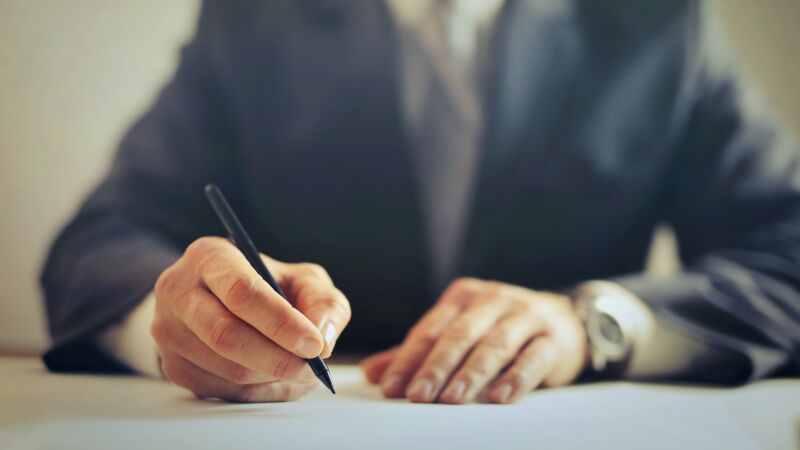 Das Bild zeigt eine Person, die einen Vertrag unterzeichnet.