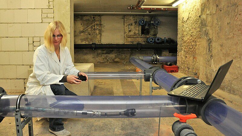 Bild zeigt, wie eine Wissenschaftlerin die „Wasserschlange“ im Modellnetz des TZW in Dresden testet. 