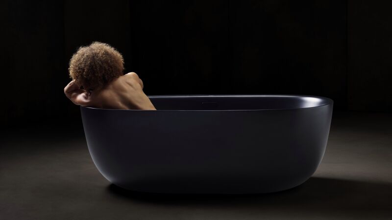 Das Bild zeigt eine dunkelhäutige Frau in einer schwarzen Badewanne.