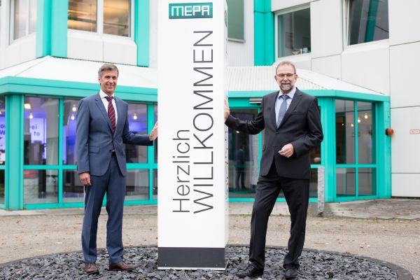Das Bild zeigt Reiner Pauli und Reinhard Menden vor dem Firmengebäude.