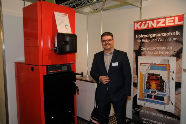 Geschäftsführer Tim Künzel von der Künzel Heiztechnik GmbH zeigt auf der IFH/INTherm 2018 seinen Kombi-Heizkessel für Holzvergaser und Öl/Gas.