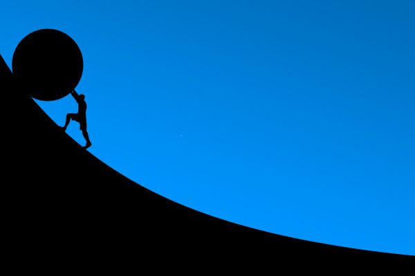 Die Silhouette eines Mannes rollt vor einem blauen Hintergrund einen Stein einen Berg hoch.
