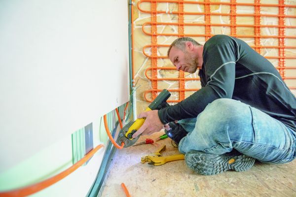 Ein Handwerker beim Einbau von Wand-Modulen für eine Trockenbau-Wandheizung/Kühlung.