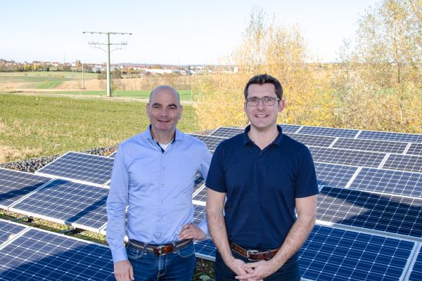 Zwei Männer stehen vor Solarmodulen.