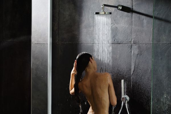 Das Bild zeigt eine Frau, die sich unter der Brause wäscht.Die Dusche ist mit den 