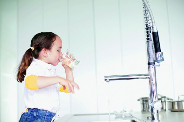 Das Bild zeigt ein Mädchen, das ein Glas Wasser trinkt.