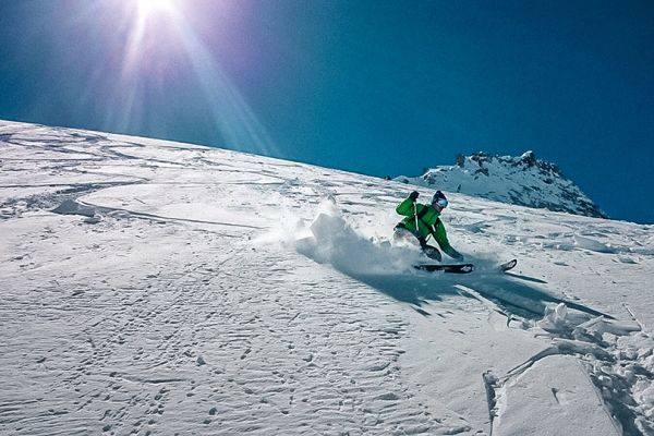Ein Mann fährt auf Skiern eine Piste hinunter.