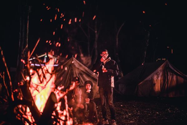 Ein Mann steht neben einem Lagerfeuer.