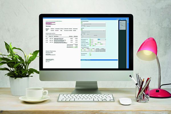 Ein Computer-Bildschirm, der auf einem Schreibtisch neben einer Tastatur, Lampe, Pflanze, Tasse und einem Stiftebecher steht.